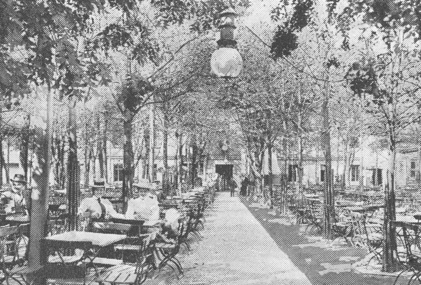 In der Mitte des Schwarzweißfotos sieht man eine sommerliche Baumallee, die direkt auf ein großes Gebäude zuführt. links sitzen an Biertischen zwei Damen mit Hüten und ein Herr mit Hut. Hinten vor dem Haus stehen auch Menschen und unterhalten sich.