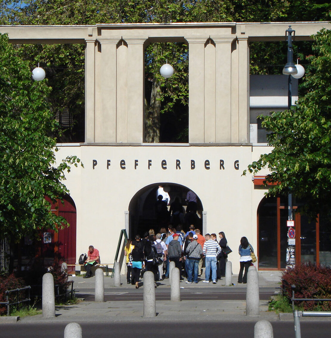 Eine große Gruppe von Menschen betritt den Pfefferberg durch das Stufenportal des Geländes zur Schönhauser Allee