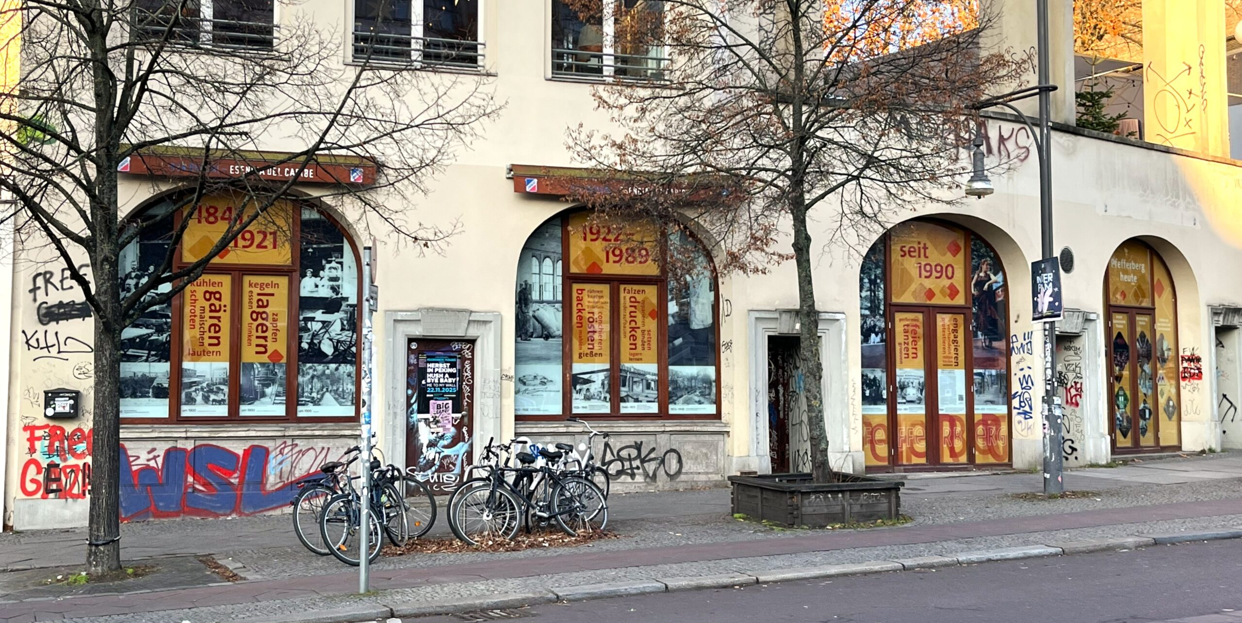 Beklebte Rundbogen-Fenster an einer Straße , davor Fahrräder und Bäume